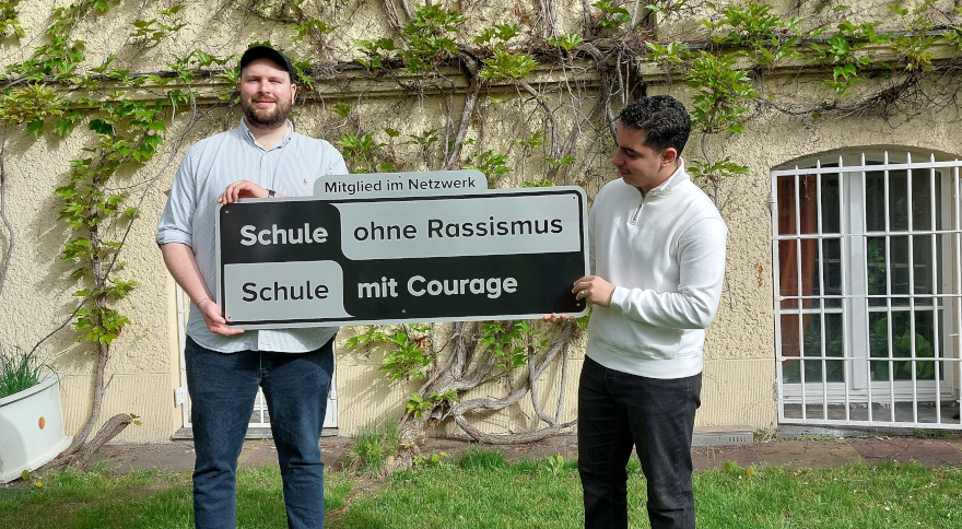 Zwei Personen halten das Schild mit dem Zusatz "Mitglied im Netzwerk"