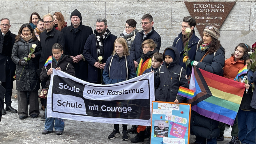 Gruppenbild vor der Gedenktafel am Nollendorfplatz. chüler*innen halten das Banner von SOR-SMC.