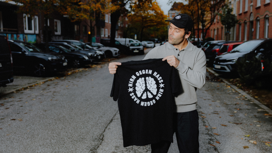 Bosse hält ein T-Shirt mit dem "Hirn gegen Hass"-Motiv