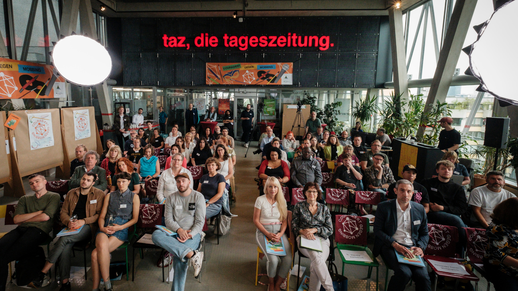 Blick auf das Publikum, im Hintergrund ein großes Banner mit der Aufschrift 