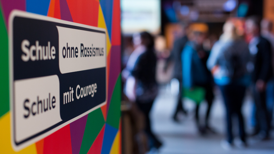 Roll-up von SOR-SMC, im Hintergrund Menschen in einer Austauschsituation
